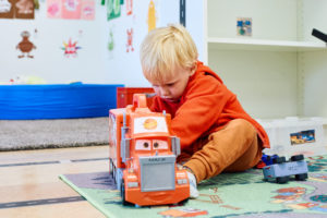 Liten pojke leker koncentrerat med en leksakslastbil på förskolans bilmatta.