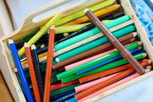 Färgpennor i olika färger ligger i en trälåda